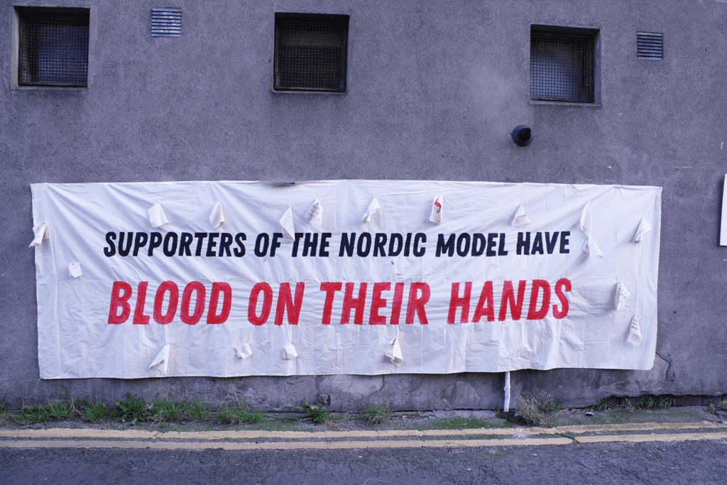 Supports of the Nordic Model have blood on their hands, written on a banner in black 