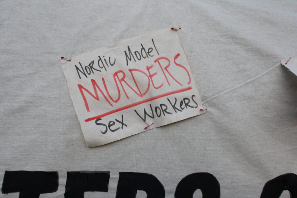 Nordic Model Murders Sex Workers, handwritten on cloth with black and red markers